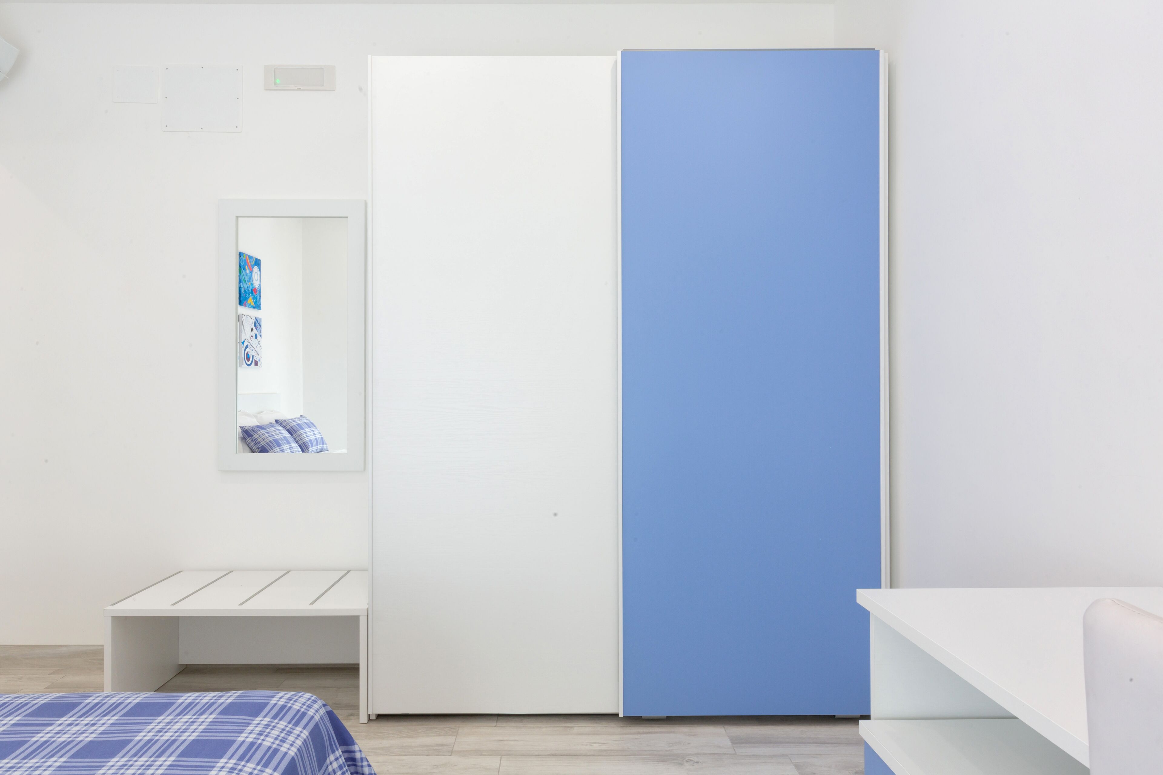 Une chambre à coucher avec un lit, une armoire, un banc et un miroir.