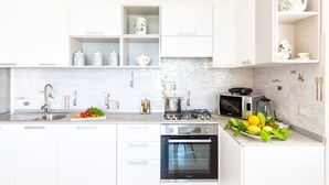 Una cocina moderna con armarios blancos, horno empotrado, microondas y estufa a gas.