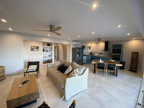 Relax in a spacious living area with a sofa set, dining table, and kitchen island.