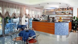 A modern restaurant with a curved bar, glass dining area, and a view of the outdoors.