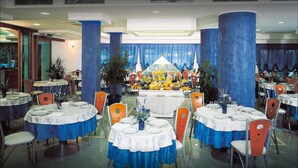 A dining area with round tables, blue tablecloths, and orange chairs.