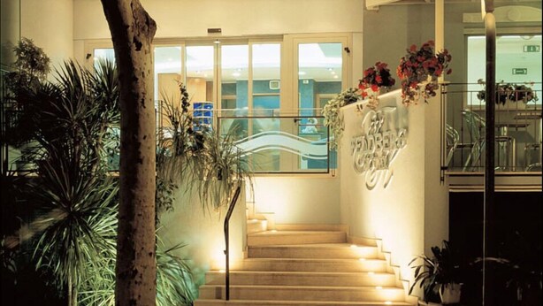 A staircase with a handrail, leading to a reception area with a glass door and a sign above it.
