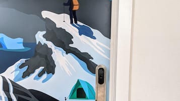 Puerta con un mural de un excursionista en la cima de una montaña, una tienda de campaña y un cartel que dice "ROOM 7".