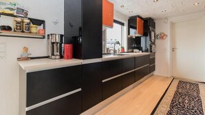 Una cocina moderna con armarios negros, una cafetera de acero inoxidable y un hervidor rojo.