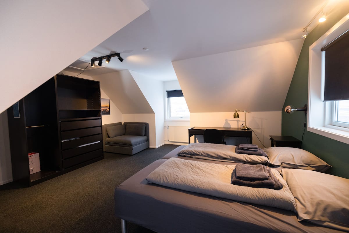 A modern bedroom with a loft bed, a desk, and a chair.