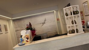 En receptionsdisk med en väggmålning föreställande fåglar, en växt och ett nyckelställ.