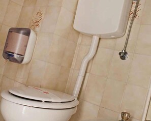 A toilet with a lid, a hand dryer, and a toilet paper holder on the wall. - Hotel Mauri (Rimini)