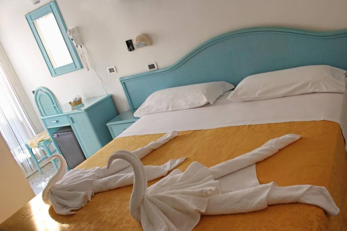 Una habitación de hotel con una cama, un tocador con espejo y una mesita.