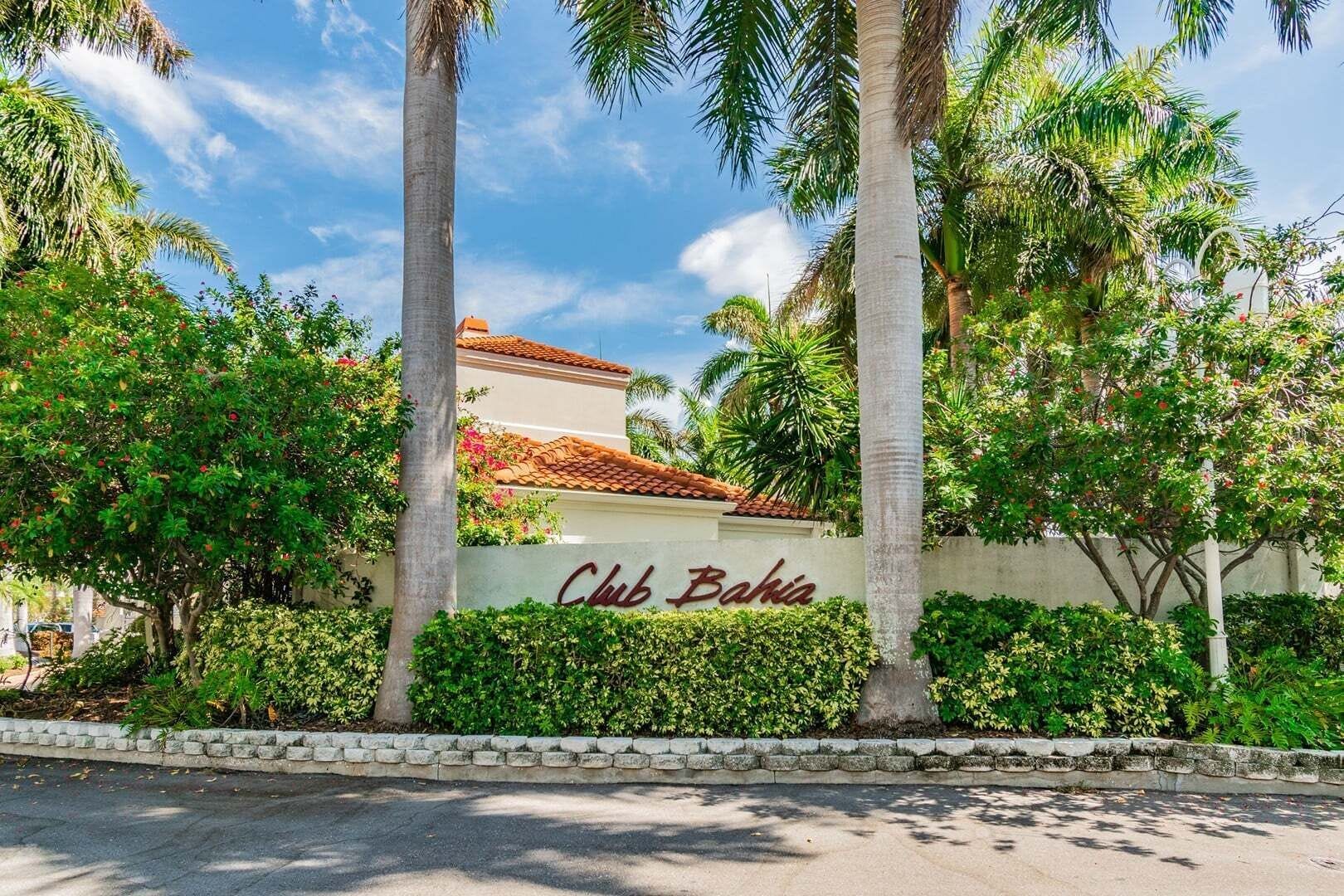 A building with a sign reading 'Club Bahia' surrounded by lush greenery and palm trees.