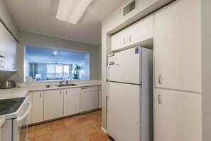 Eine Küche mit Einbauofen, Kühlschrank und einem Fenster mit Blick auf Palmen.