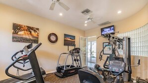 Un gimnasio en casa con cintas de correr, elípticas y equipo de pesas.