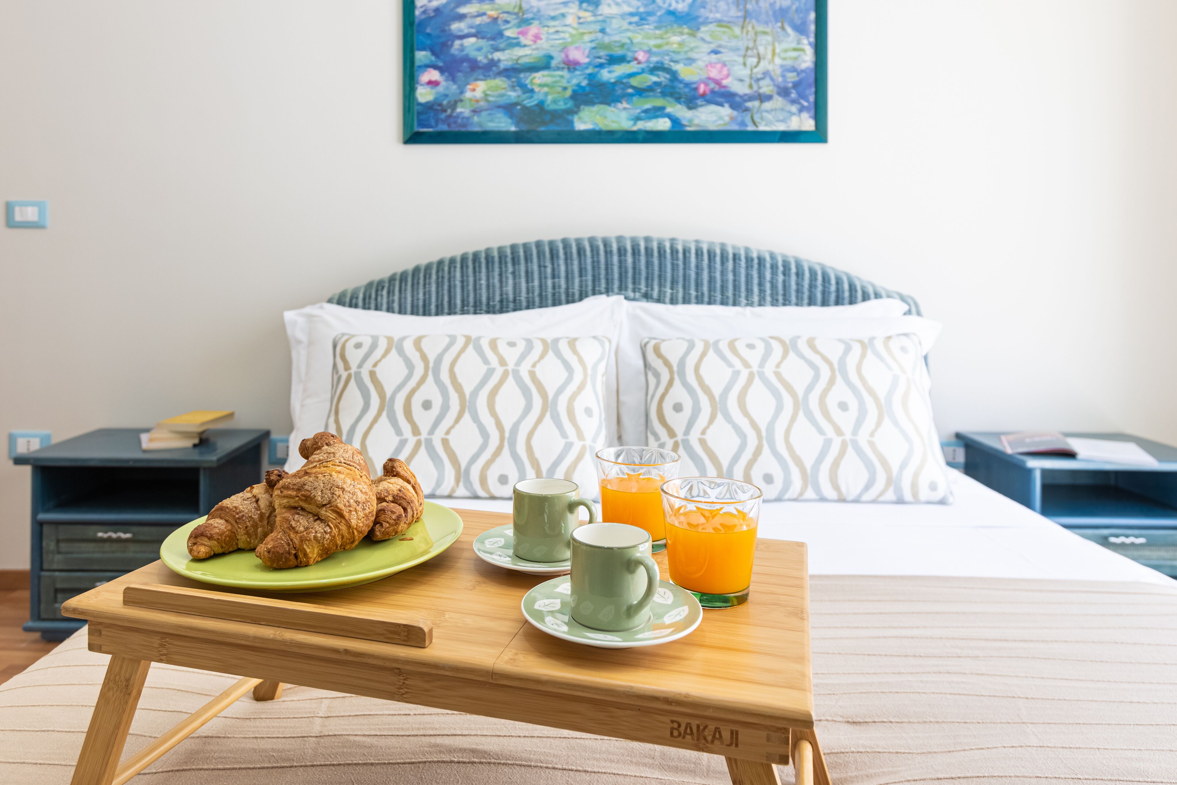 Ein ordentlich gedeckter Frühstückstisch mit Croissants, zwei Tassen und Gläsern Orangensaft in einem Hotelzimmer.