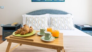 A neatly arranged breakfast table with croissants, two mugs, and glasses of orange juice in a hotel room.
