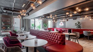 En moderne restaurant med røde læderbænke, runde borde og hængende, sfæriske lamper.