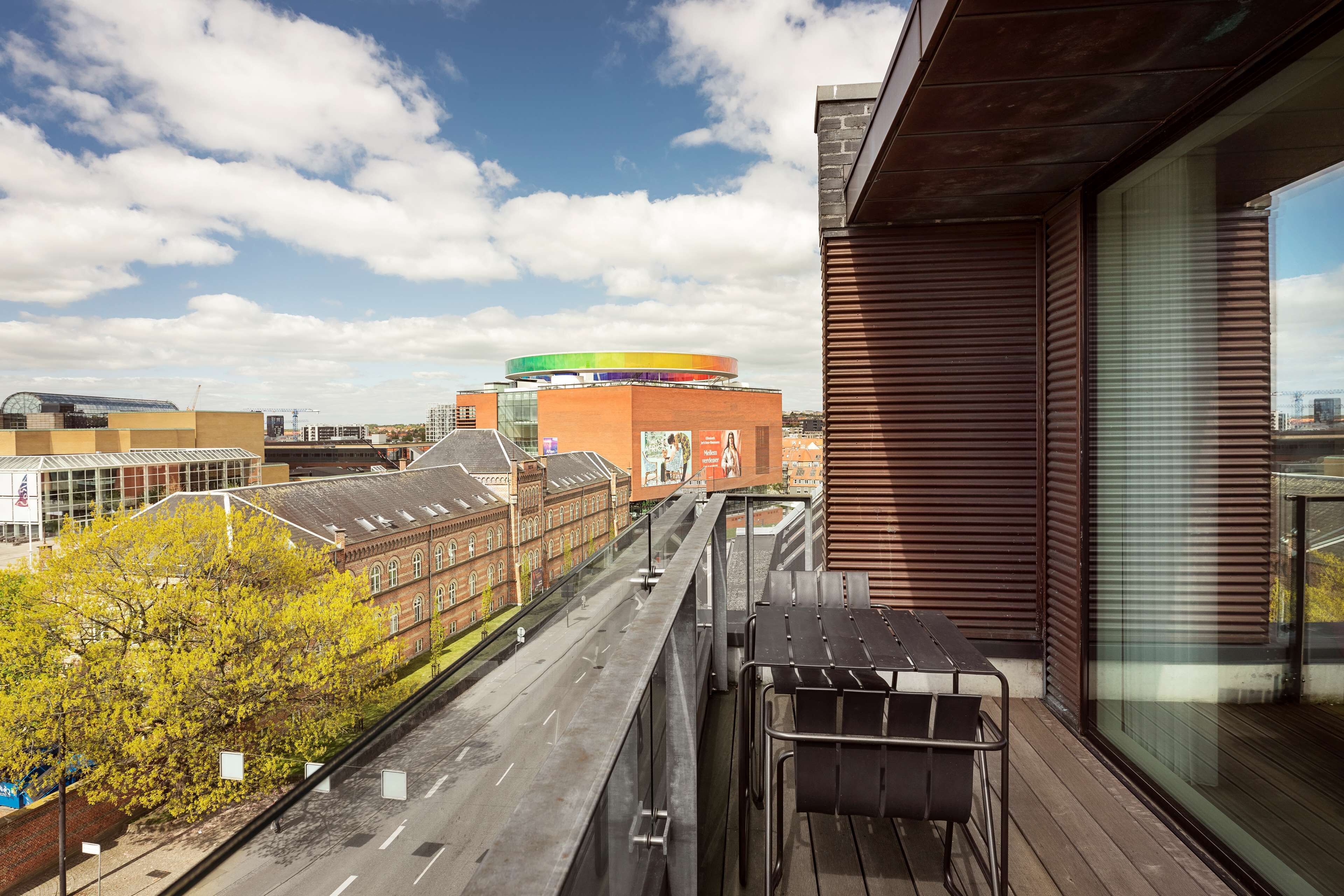 A balcony with a view of a cityscape, including a distinctive building with a colorful circular top.