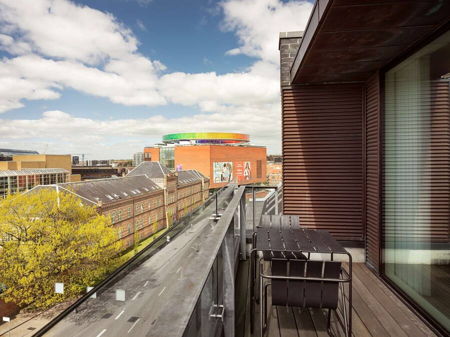 A balcony with a view of a cityscape, including a distinctive building with a colorful circular top.