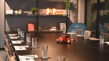 A conference room with a long table, chairs, and a red toy car on the table.