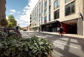 A modern building with large windows, a bike parking area, and a pedestrian crossing.