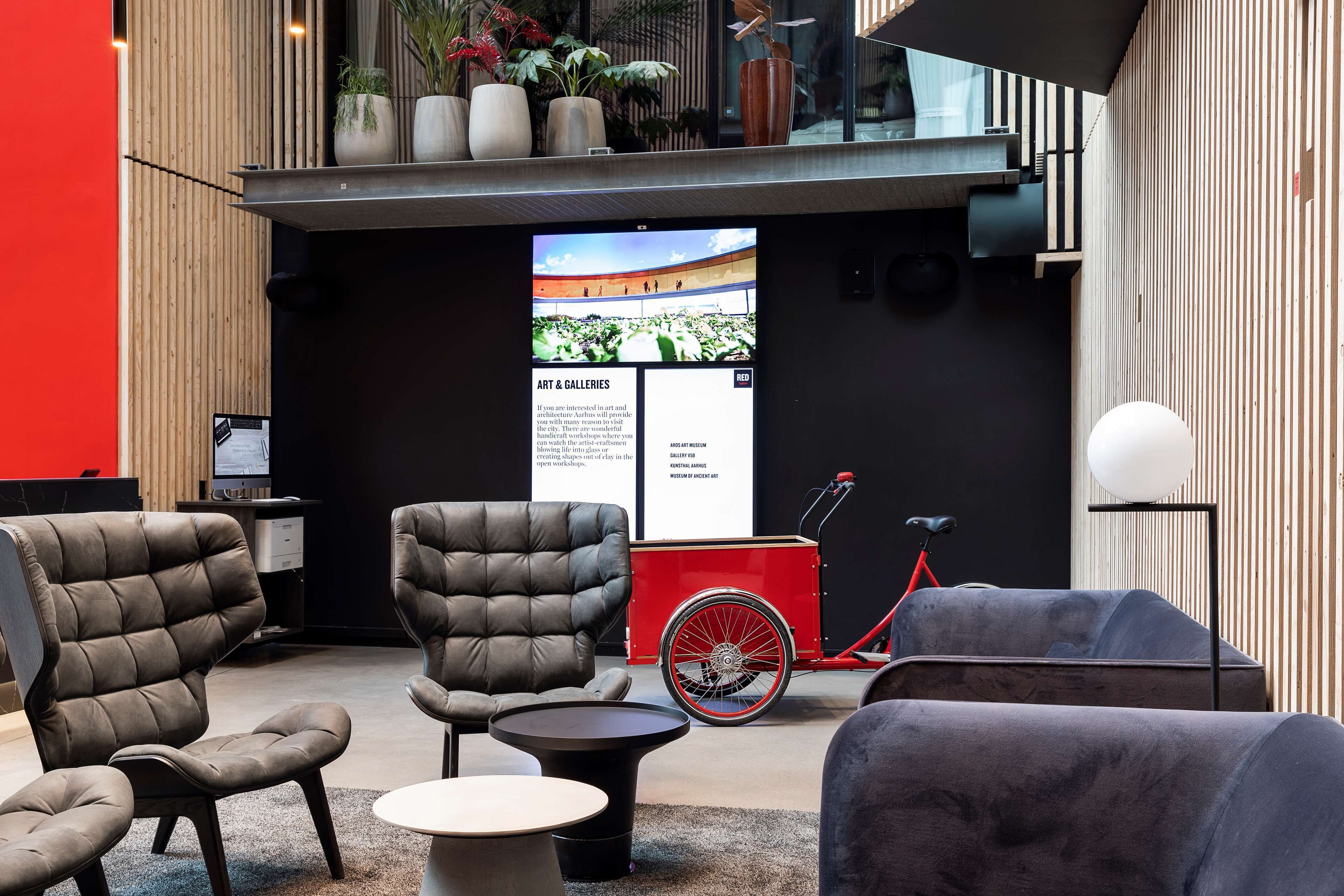 Un hall d’entrée moderne avec des fauteuils en cuir, une petite table ronde et un vélo rouge.