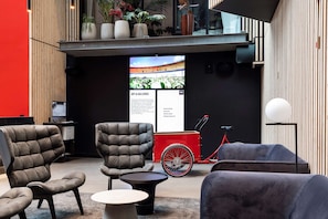 A modern lobby with leather armchairs, a small round table, and a red bicycle.