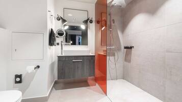 Une salle de bain moderne équipée de toilettes, d’un meuble-lavabo, d’un miroir et d’une douche.