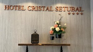 A reception desk with a sign reading "HOTEL CRISTAL SETUBAL" and a floral arrangement. - Hotel Cristal Setubal (Setubal)