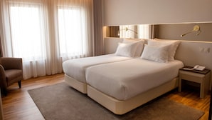 A hotel room with a double bed, a bedside table with a phone, and a chair. - Hotel Cristal Setubal (Setubal)