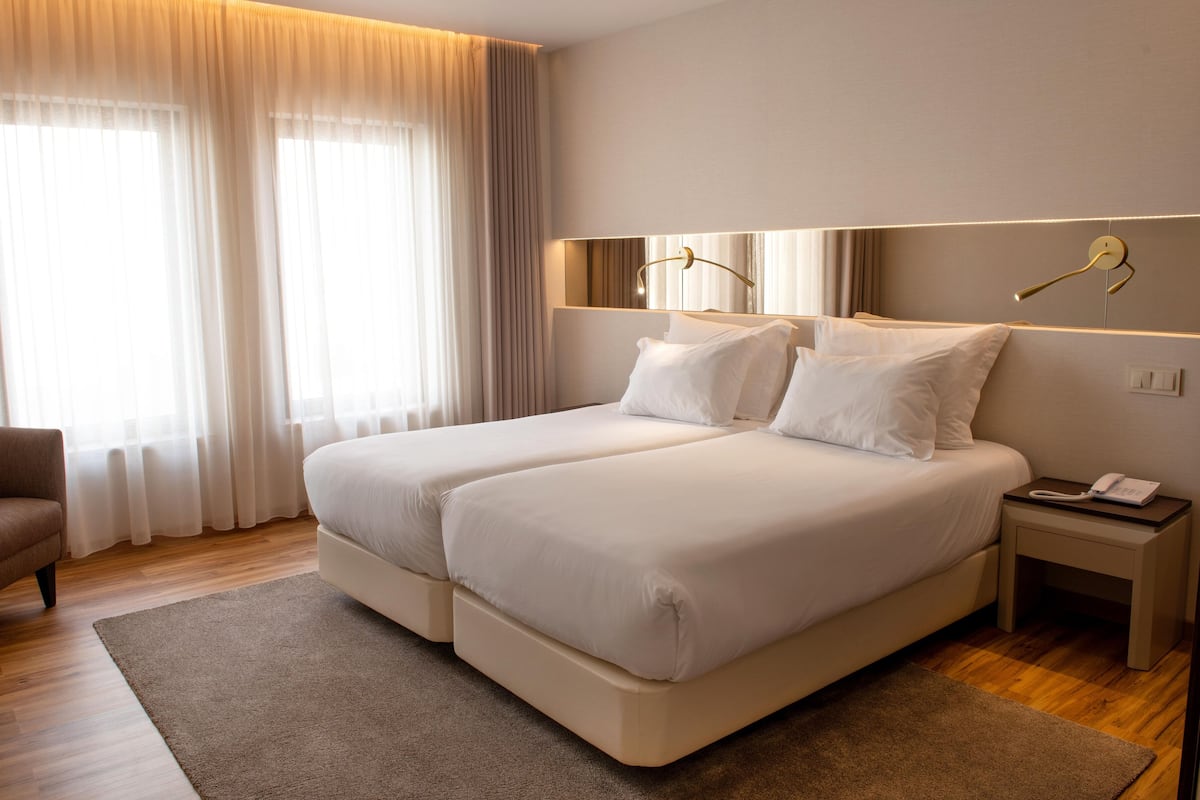A hotel room with a double bed, a bedside table with a phone, and a chair.