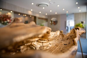 A close-up of a textured, organic-shaped object, possibly a decorative item, in a well-lit indoor setting with a modern ceiling and ambient lighting.