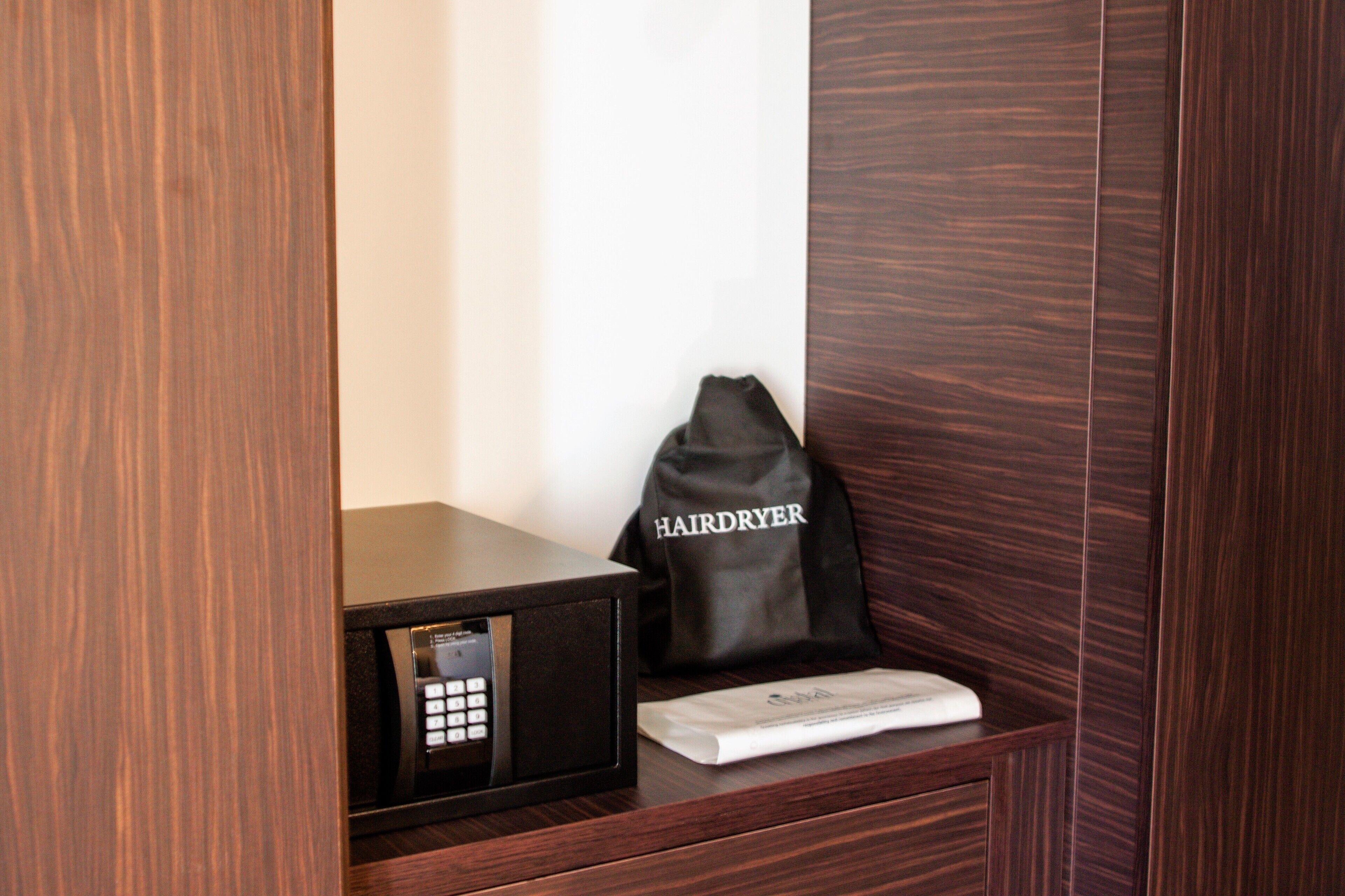 Un mueble de madera con un secador de pelo y una bolsa etiquetada 'HAIRDRYER' encima.