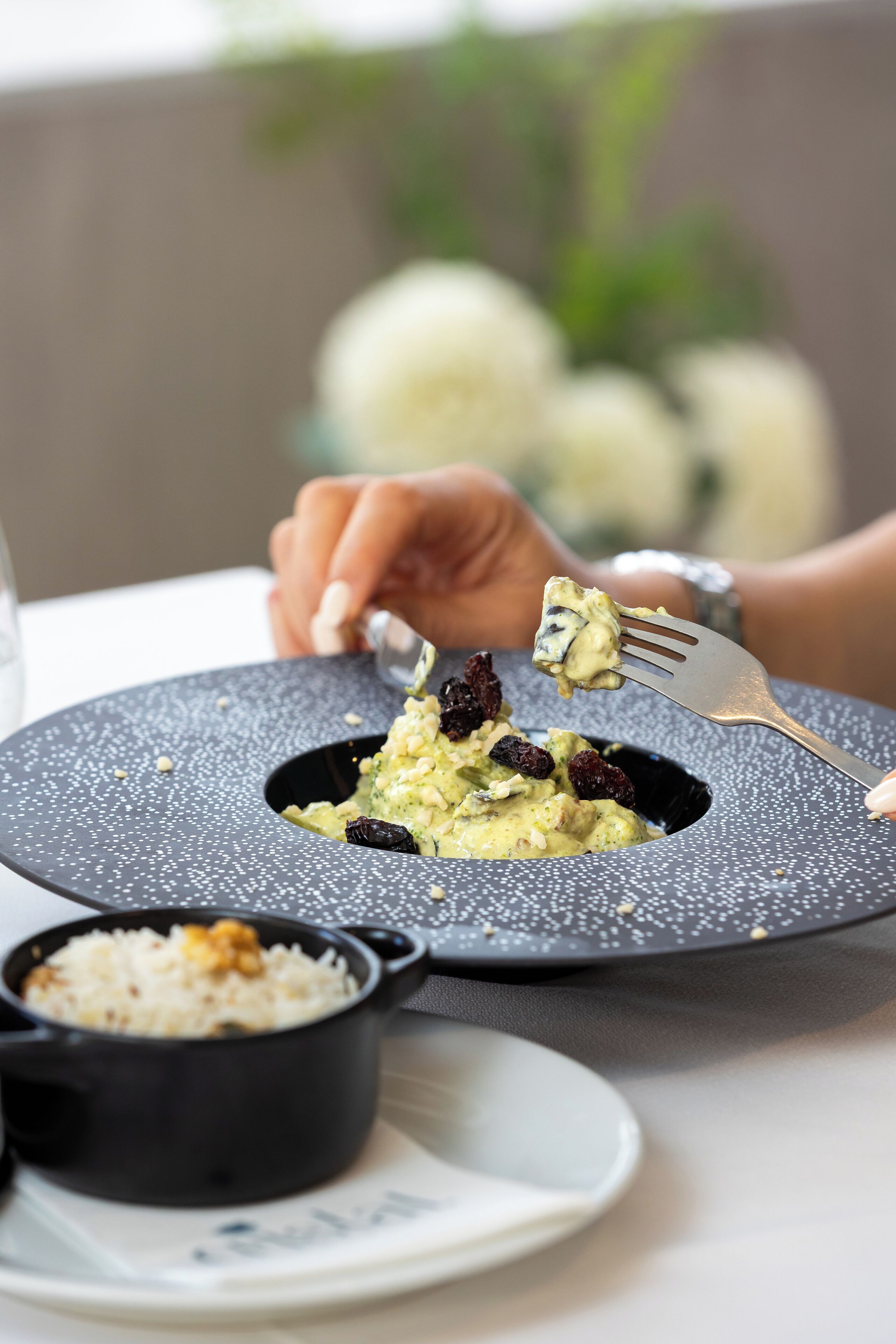 A dining table with a plate of food, a small bowl of rice, and a fork.
