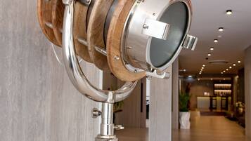 Un couloir moderne et bien éclairé, orné d’un objet décoratif en bois et en métal, fixé sur un trépied.