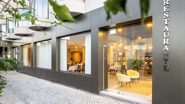A modern restaurant with a glass facade, interior seating, and a visible outdoor seating area. - Hotel Cristal Setubal (Setubal)
