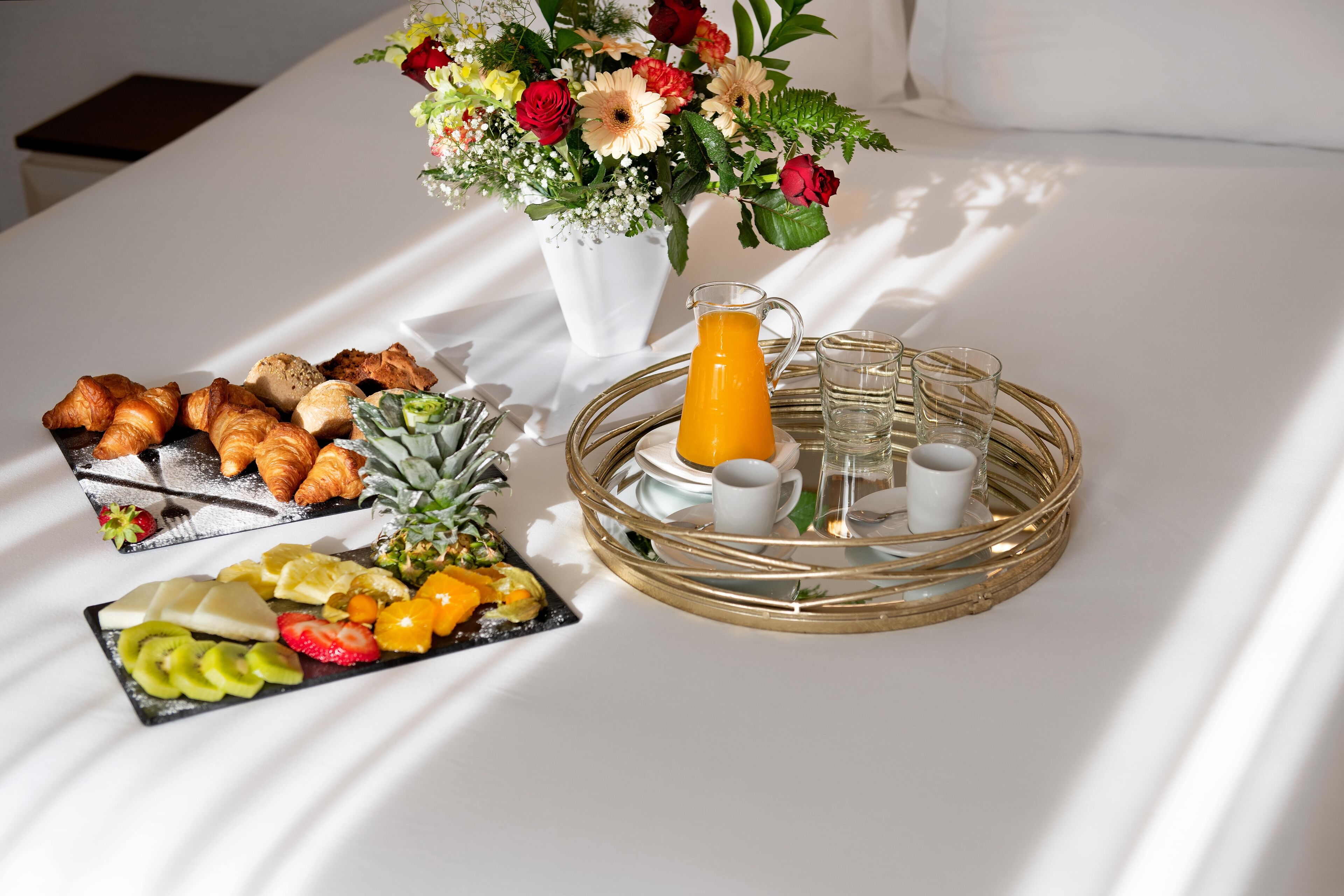 Un bufé de desayuno con pasteles, frutas y una jarra de jugo sobre un mantel blanco.