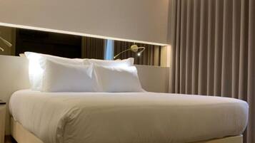 Una camera d'albergo moderna con un letto grande, un comodino, una lampada e una finestra con tende.