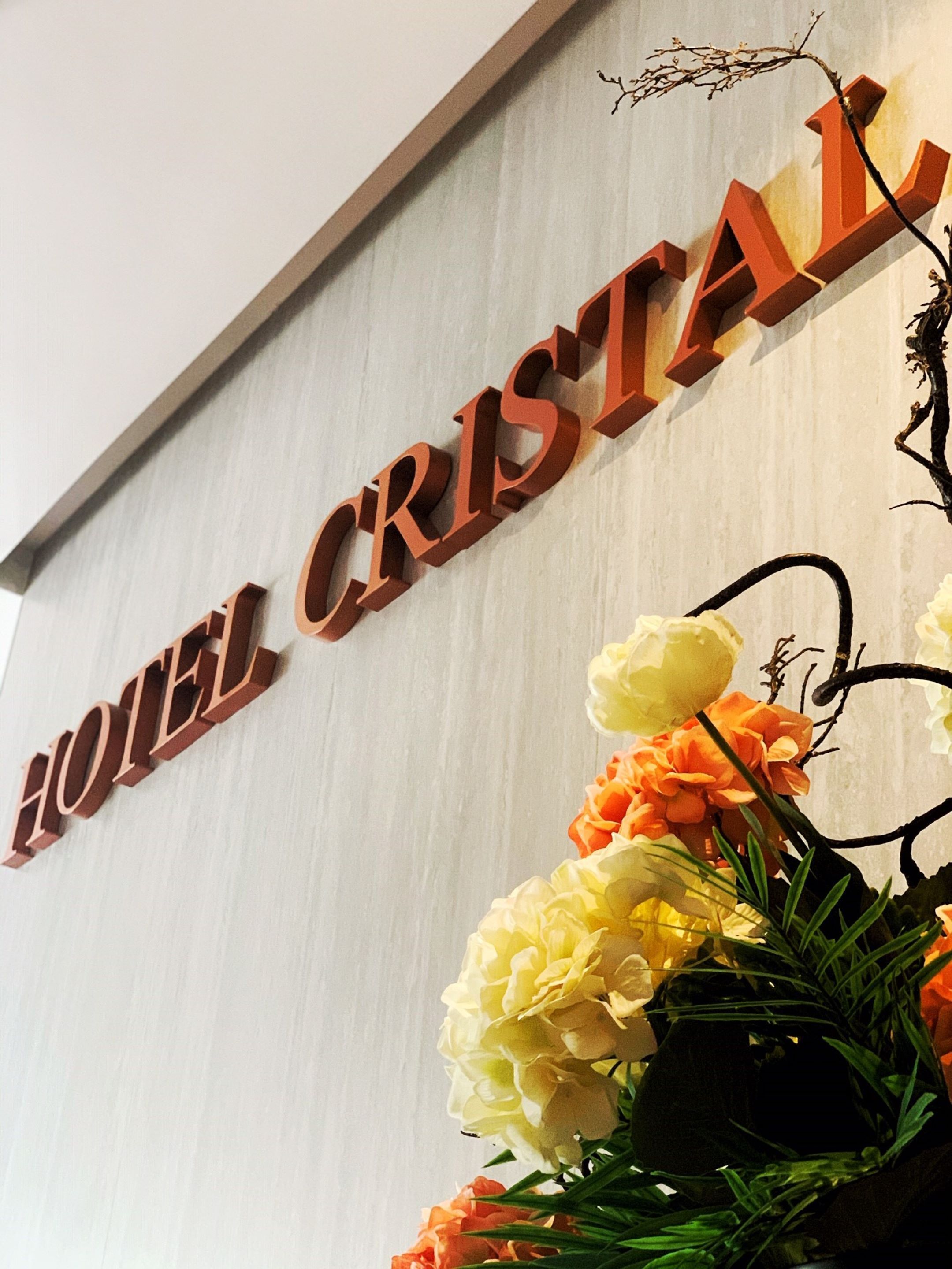 A sign for HOTEL CRISTAL with a floral arrangement below it.