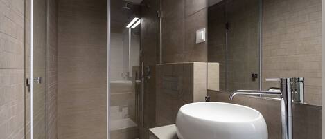 A modern bathroom with a glass-enclosed shower, a white sink, and a toilet.