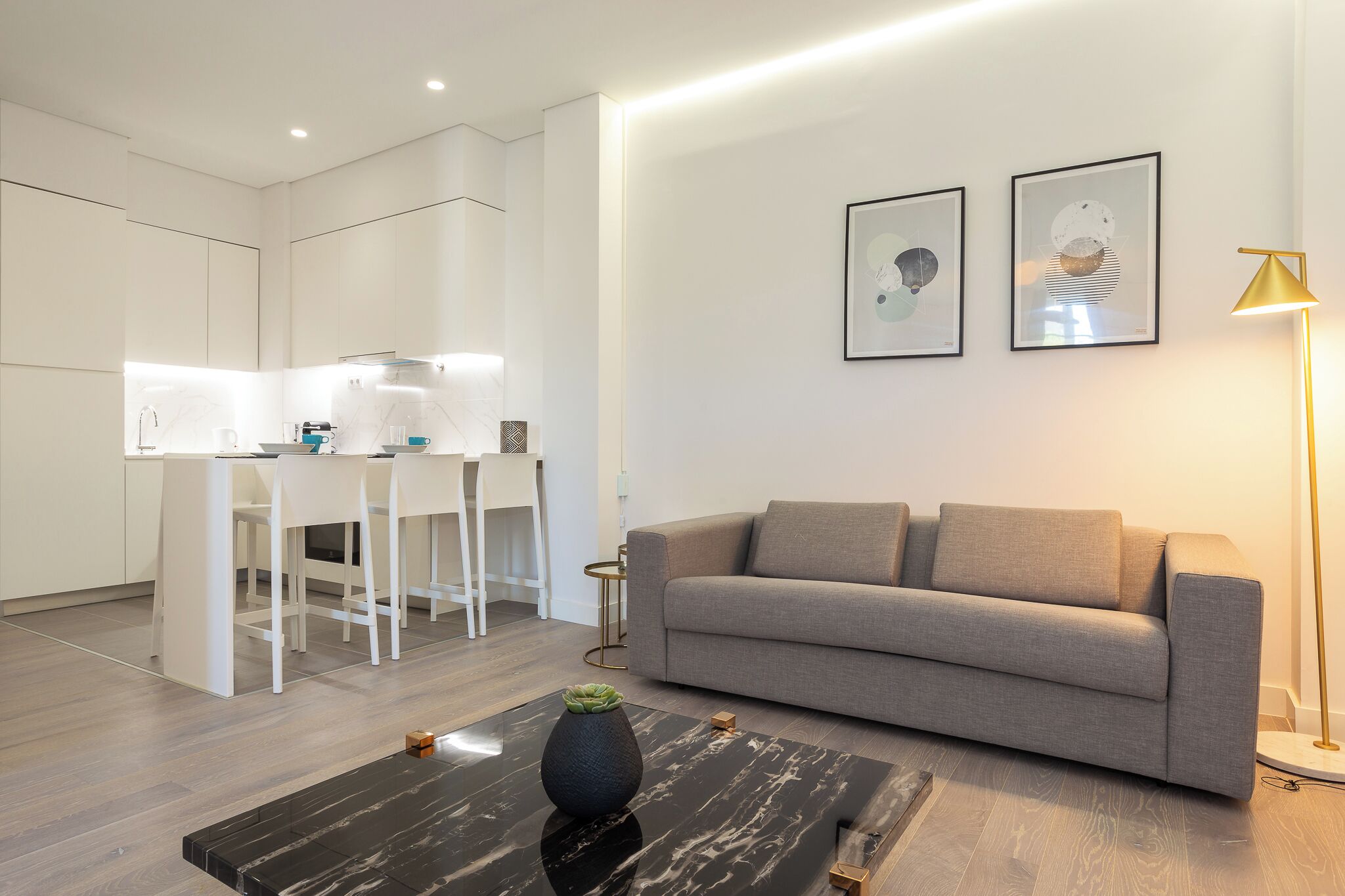 A modern living room with a sofa, a coffee table, and a dining area with chairs and a table.