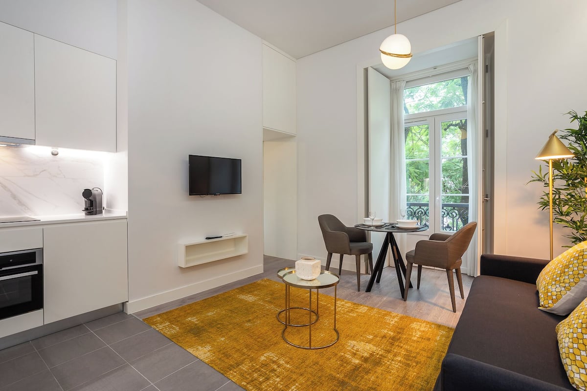 A modern kitchen with a built-in oven, a TV, and a dining area with a table and chairs.