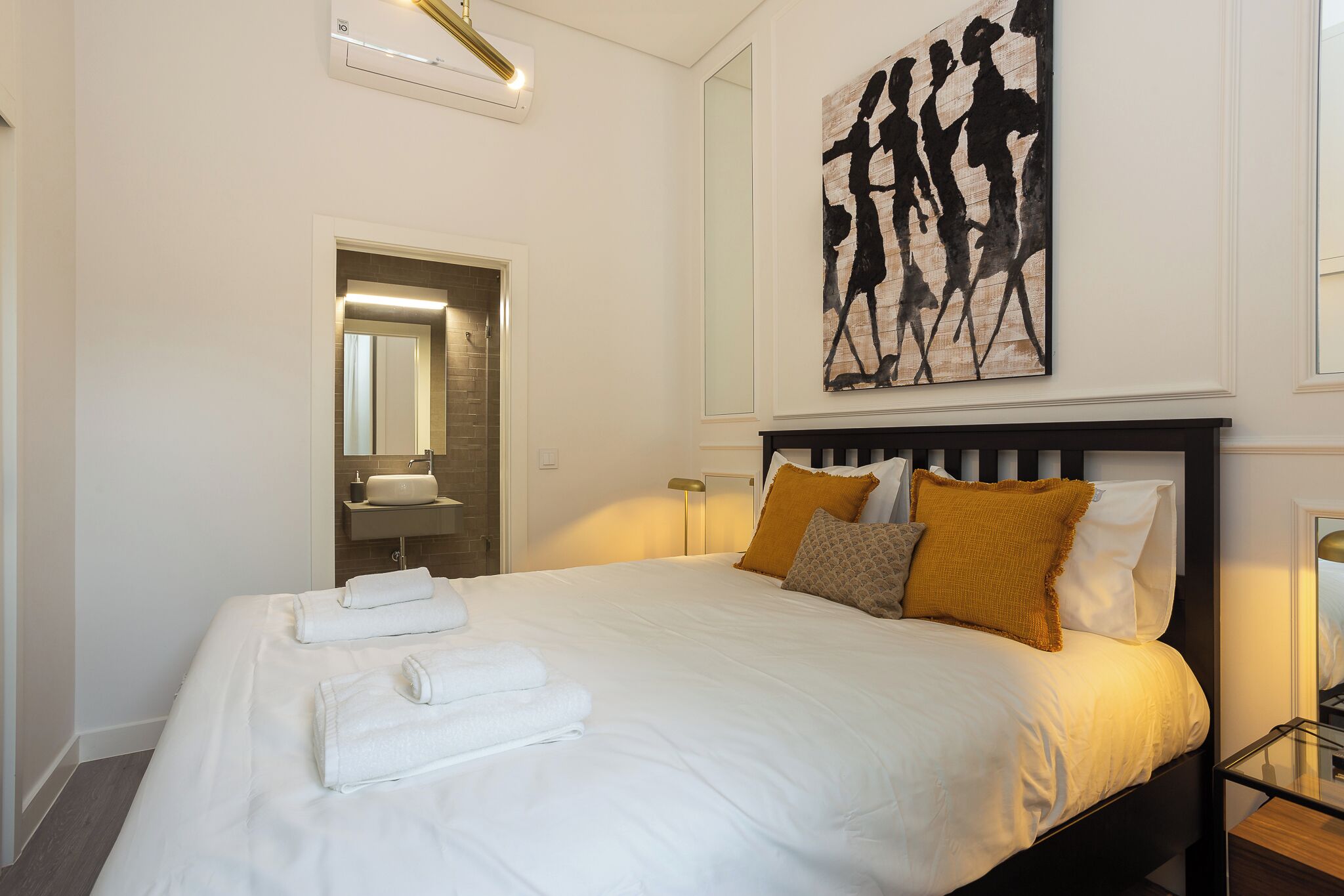 Una habitación de hotel con una cama, un baño con espejo y un cuadro en la pared.