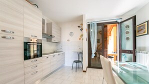 Een moderne keuken met een eethoek, met een glazen tafel en een stoel.