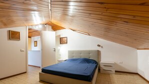 Een slaapkamer met een bed, nachtkastjes en een houten plafond.