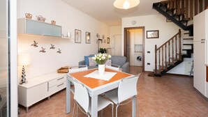 Une cuisine moderne avec des meubles blancs, une table à manger en bois et un escalier avec des rampes en bois.