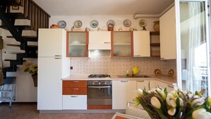 Une cuisine moderne avec des meubles blancs, un four en acier inoxydable et un coin repas comprenant une table et des chaises.