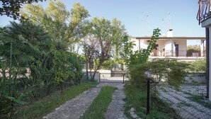 Un chemin menant à un bâtiment à la façade blanche et doté d’un balcon.