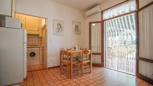 Une cuisine compacte équipée d’un lave-linge, d’une table à manger avec des chaises et d’une grande fenêtre avec des rideaux.