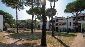 A courtyard with trees, a paved walkway, and residential buildings. - Spinnaker (Comacchio)