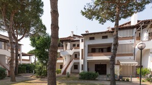 A residential building with multiple floors, a central staircase, and a small garden area with trees and shrubs. - Spinnaker (Comacchio)