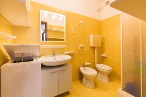 Un baño con lavamanos, espejo, bidé, inodoro y ducha.