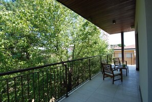 A balcony with a wooden ceiling, metal railing, and two wooden chairs with cushions. - Tasso (Ferrara)